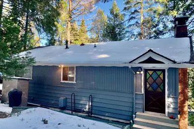 a blue house with a snow covered roof at Idyllic Cabin in the Woods Cozy Crestline Retreat in Arrowhead Highlands