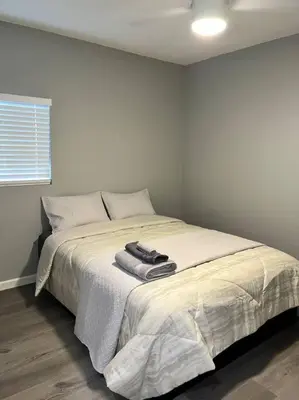 a white bedroom with a bed with two towels on it at Lux Cozy Experience Elegance in San Bernardino