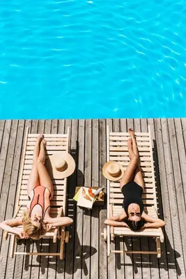 two women laying on chairs next to a swimming pool at Luxury ApartStudio Marina Del Rey Pool, Gym, Parking, Jacuzzi, BBQ in Los Angeles