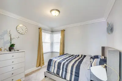a bedroom with a bed and a clock on the wall at Furnished Patio! South Central Home 14 Mi to DTLA in Compton