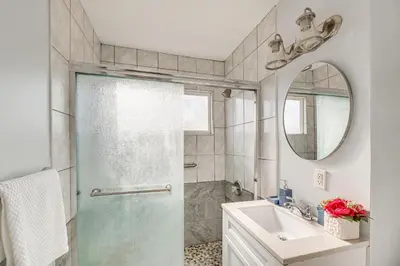 a bathroom with a shower and a sink and a mirror at Furnished Patio! South Central Home 14 Mi to DTLA in Compton