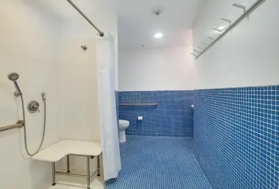a bathroom with a shower with a toilet and blue tiles at Venice Breeze Suites in Los Angeles