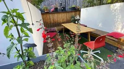 a garden with a wooden table and a red chair at Rumi in Los Angeles