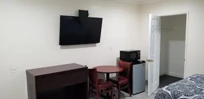 a room with a small table and a tv on the wall at Hollywood Park Motel in Inglewood
