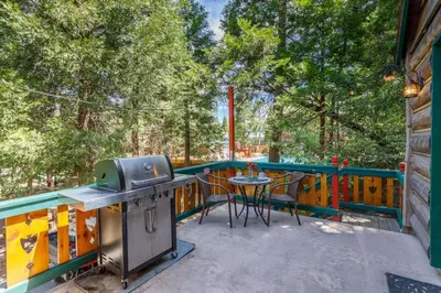 a patio with a grill and a table on a deck at Arrowhead Pine Rose Cabins in Twin Peaks