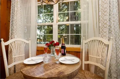 a dining room table with two chairs and a window at Arrowhead Pine Rose Cabins in Twin Peaks