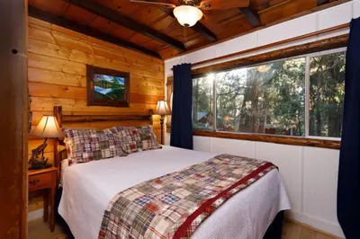 a bedroom with a bed and a window at Arrowhead Pine Rose Cabins in Twin Peaks