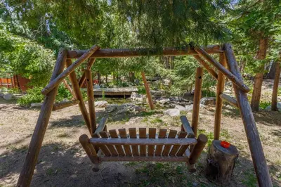 a wooden swing in a park with a tree at Arrowhead Pine Rose Cabins in Twin Peaks