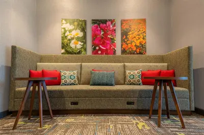 a couch with two tables in a room with paintings at Hampton Inn By Hilton Santa Clarita-Valencia in Santa Clarita
