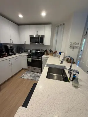 a kitchen with white cabinets and a stainless steel sink at Canyon Country Cozy Apartment, Pool and Jacuzzi in Santa Clarita