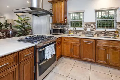 a kitchen with wooden cabinets and a stove top oven at Central LA Bliss: 5 BR Home, BBQ, Perfect Location in Los Angeles
