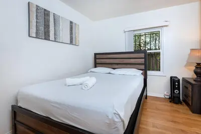 a bedroom with a bed with white sheets and a window at Central LA Bliss: 5 BR Home, BBQ, Perfect Location in Los Angeles