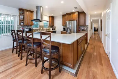 a kitchen with wooden cabinets and a island with bar stools at Central LA Bliss: 5 BR Home, BBQ, Perfect Location in Los Angeles