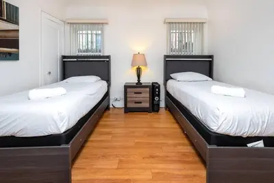 two twin beds in a room with wooden floors at Central LA Bliss: 5 BR Home, BBQ, Perfect Location in Los Angeles