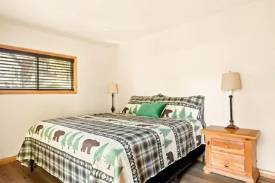 a bedroom with a bed and a wooden night stand at Lakeside Paradise Escape in Big Bear Lake