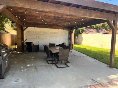 a patio with a wooden pergola with a table and chairs at An Amazing comfortable home front middle unit 1q bed and other room with sofa in Los Angeles