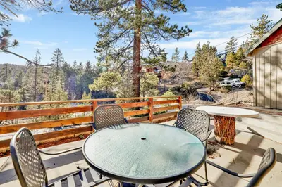 a table and chairs on a patio with a view at Pleasant Pause#1864 in Fawnskin