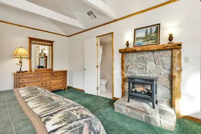 a bedroom with a stone fireplace and a bed at Pleasant Pause#1864 in Fawnskin