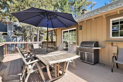 a wooden table with chairs and an umbrella on a deck at All about fun #1149 in Big Bear Lake