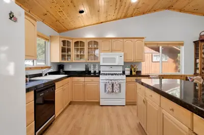 a kitchen with wooden cabinets and a white stove top oven at River rock lodge #1953 in Big Bear Lake