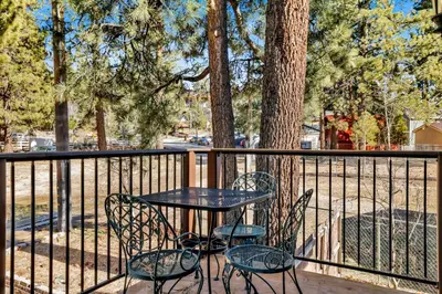 a table and chairs on a deck with a fence at Fawnskin Chalet#1826 in Fawnskin