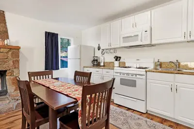 a kitchen with white cabinets and a table and chairs at The weekender #2342 in Big Bear City