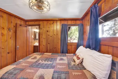 a bedroom with a bed with blue curtains and a window at Lakeview #104 in Big Bear Lake