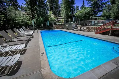 a large blue swimming pool with lounge chairs around it at Lonepine#107 in Big Bear Lake