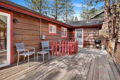 a cabin with two chairs and a grill on a wooden deck at Moulin rouge #2055 in Big Bear Lake