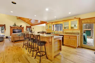 a kitchen with wooden cabinets and a bar with bar stools at Flitterbick lodge #2246 in Fawnskin