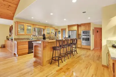 a kitchen with wooden cabinets and a bar with stools at Flitterbick lodge #2246 in Fawnskin
