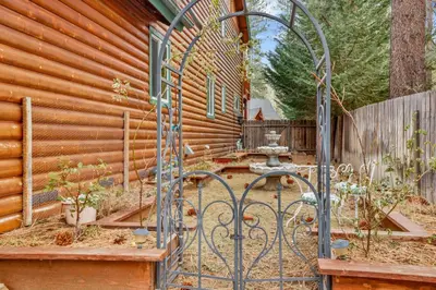 a garden with a gate in front of a wooden house at Flitterbick lodge #2246 in Fawnskin