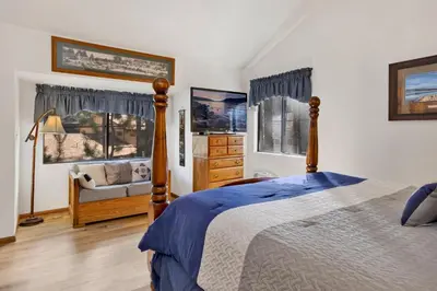 a bedroom with a bed and a chair and windows at Ski time getaway #1848 in Big Bear Lake