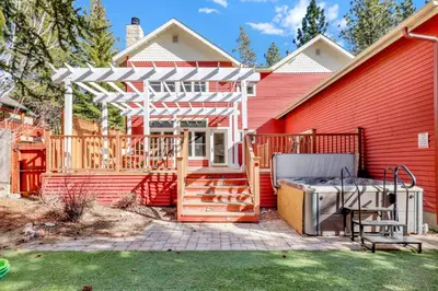 a deck with a white pergola next to a red house at The grand chalet #1989 in Big Bear Lake