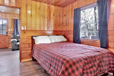 a bed in a wooden room with a window at Lupine #106 in Big Bear Lake