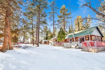 a cabin with a green roof in the snow at Lupine #106 in Big Bear Lake