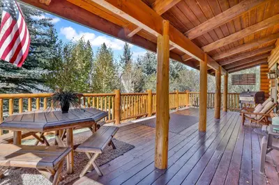 a wooden deck with a table and chairs on it at Knotty and nice #177 in Big Bear Lake
