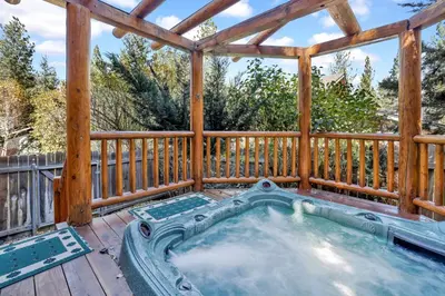 a hot tub on a deck with a wooden fence at Knotty and nice #177 in Big Bear Lake