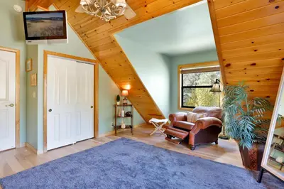 a living room with a vaulted ceiling and a staircase at Knotty and nice #177 in Big Bear Lake