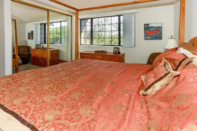 a bedroom with a large red bed and windows at Cienega getaway #1952 in Big Bear Lake