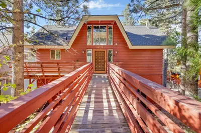 a red house with a wooden bridge leading to the front door at Fishermans paradise #1792 in Big Bear Lake