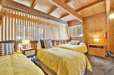 two beds in a room with wooden walls at QUAIL'S CALL #2415 in Big Bear Lake