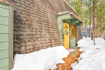 a house with a yellow door in the snow at QUAIL'S CALL #2415 in Big Bear Lake