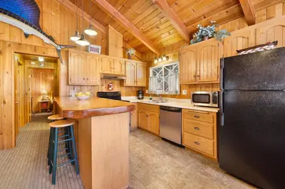 a kitchen with wooden cabinets and a black refrigerator at Oriole cottage #621 in Big Bear Lake