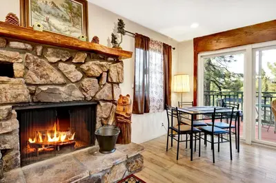 a living room with a stone fireplace and a table at A hidden asset #2379 in Big Bear Lake