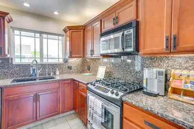 a kitchen with wooden cabinets and a stove top oven at Lovely Tustin Home with Outdoor Kitchen 3 Mi to Zoo in Tustin