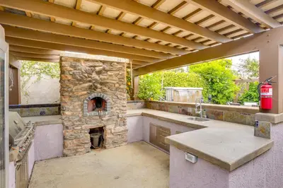 an outdoor kitchen with a stone fireplace in a house at Lovely Tustin Home with Outdoor Kitchen 3 Mi to Zoo in Tustin