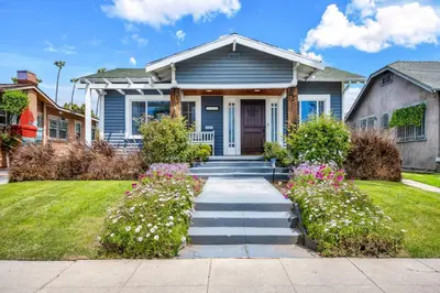 a blue house with flowers in the front yard at Gramercy Getaway in Los Angeles