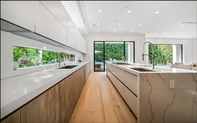 a large kitchen with white counters and wooden cabinets at Luxurious Retreat - Modern House with Pool in Los Angeles
