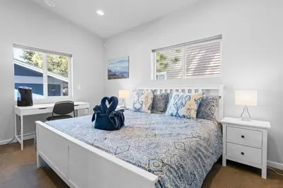 a white bedroom with a bed and two windows at Modern Lakefront Dream Home Steps from Big Bear Village in Big Bear Lake